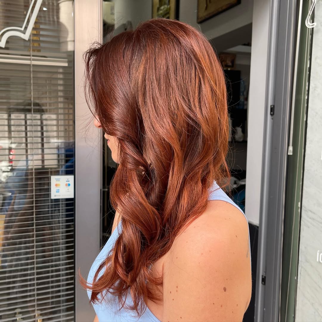 Stunning Copper Hair Summer Ideas 2026 Woman with vibrant copper hair smiling outdoors, showcasing a perfect look for copper hair summer ideas 2026. Her hairstyle complements her complexion.