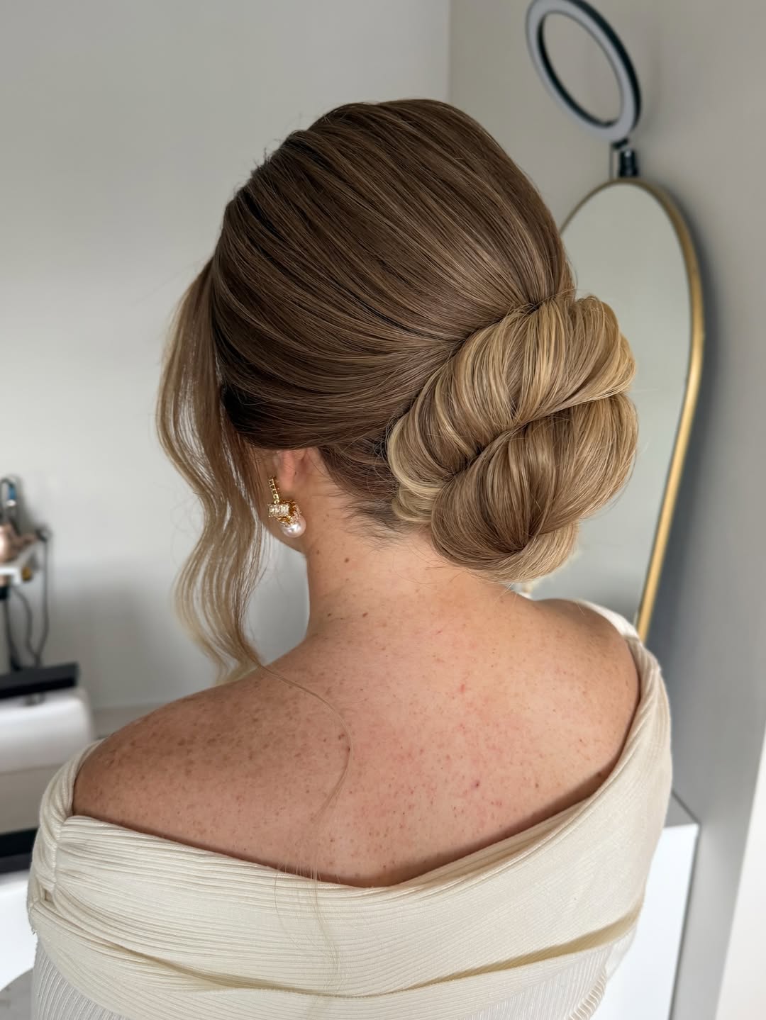 Side ponytail with stiff, overstyled curls and an ill-fitting, large fascinator, a styling mistake to avoid for summer wedding hairstyle ideas.