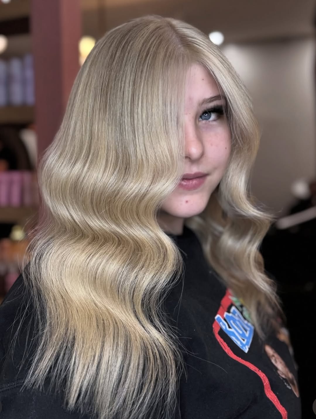 Chic Bun for Long Hair Summer Hairstyles 2026 A woman with long blonde hair styled in a chic, voluminous bun, perfect for long hair summer hairstyles 2026. She wears a cream-colored off-the-shoulder top for a sophisticated look.