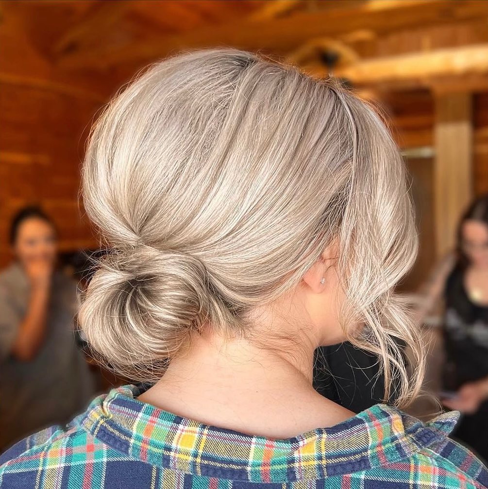 Effortless Low Braid: Simple Summer Hairstyles 2026 Close-up of a woman with long, sun-kissed blonde hair styled in a low, loose braid, perfect for simple summer hairstyles 2026. She is wearing a white linen top, emphasizing effortless summer style.