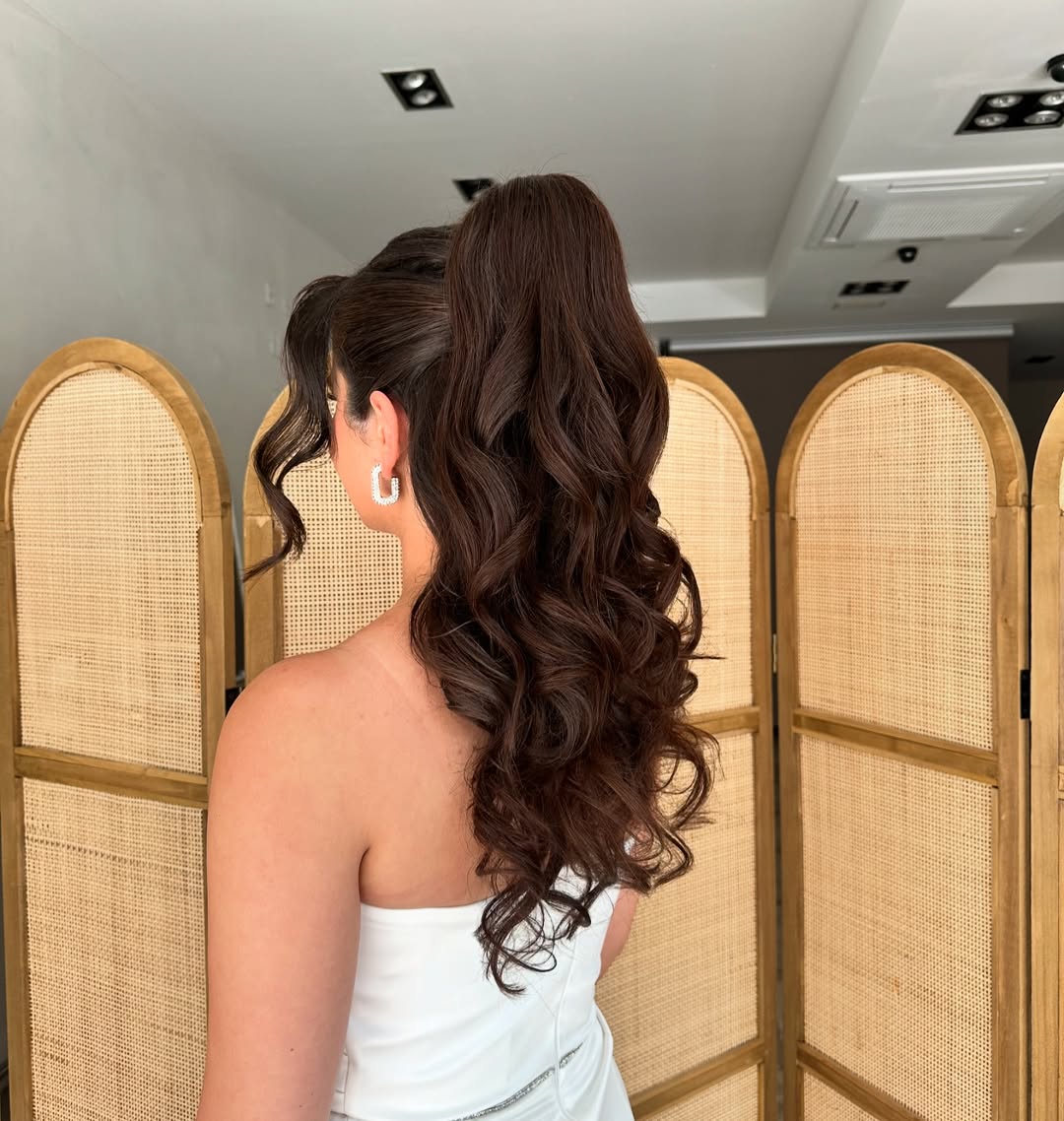 A beautiful real bride with a classic chignon bun, delicate floral hairpins, and wispy face-framing pieces, perfect for summer bride hairstyles 2026.