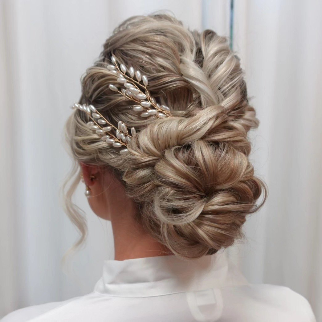 Elegant brunette bride showcasing a side-swept bun with delicate pearl hairpins, perfect for stunning summer bride hairstyles 2026. This romantic updo complements a strapless wedding gown.