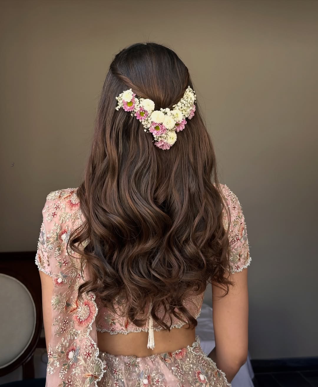 Beautiful bride with a side-swept wavy summer bride hairstyle, adorned with delicate white floral accessories for her elegant wedding day.