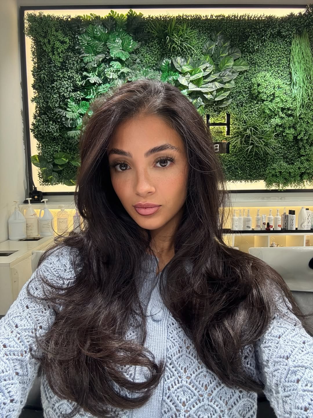 Model with long, wavy dark hair and subtle auburn highlights, perfect for captivating summer dark hair looks 2026. She wears a flowy white sundress, ideal for a beach vacation or casual summer day.