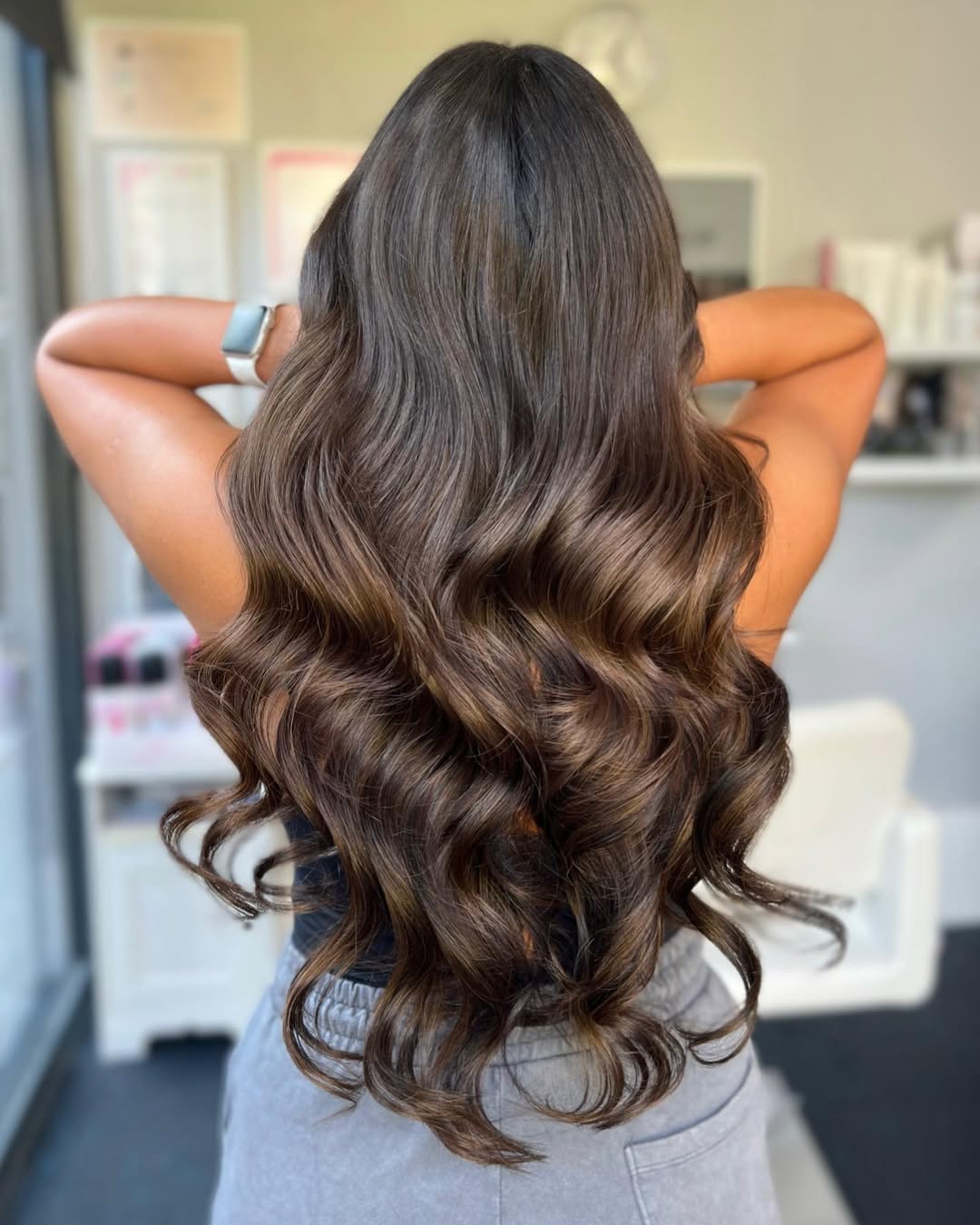 Beautiful woman with voluminous, glossy dark brown hair cascading over her shoulders, wearing a flowing white maxi dress; perfect for summer dark hair looks 2026.