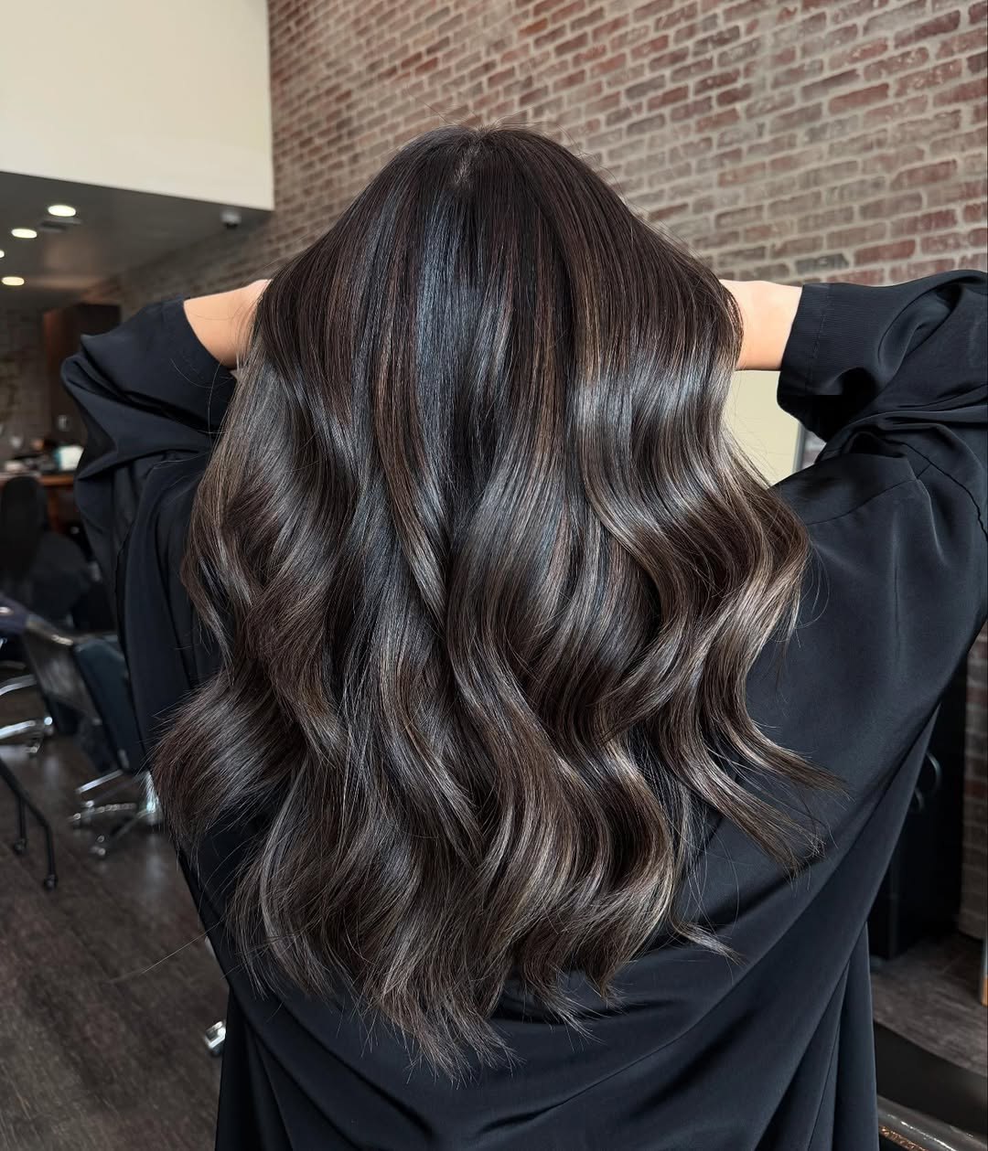 Sleek high ponytail with a loose, face-framing curl, perfect for summer dark hair looks 2026. This elegant style features glossy black hair, ideal for formal summer events or a chic everyday aesthetic.
