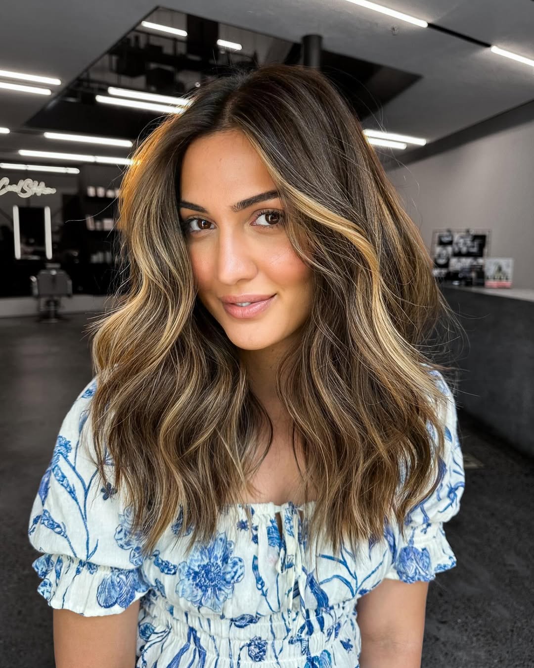 Effortless Messy Bun: Best Summer Hairstyle Idea 2026 Beautiful woman with a chic, effortless messy bun, a perfect summer hairstyle idea for 2026, paired with a casual white top and delicate gold earrings for a relaxed, elegant look.