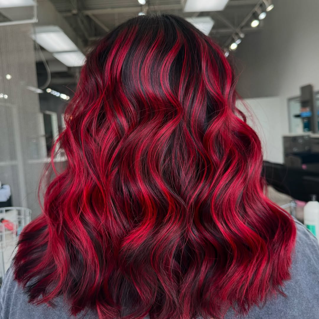 Stunning Cherry Noir Balayage: Summer Red Hair Looks 2026 Beautiful woman with cherry noir balayage waves, a trendy summer red hair looks 2026. Her long, flowing hair features dark roots blending into vibrant ruby ends, styled in soft curls, perfect for a chic evening.