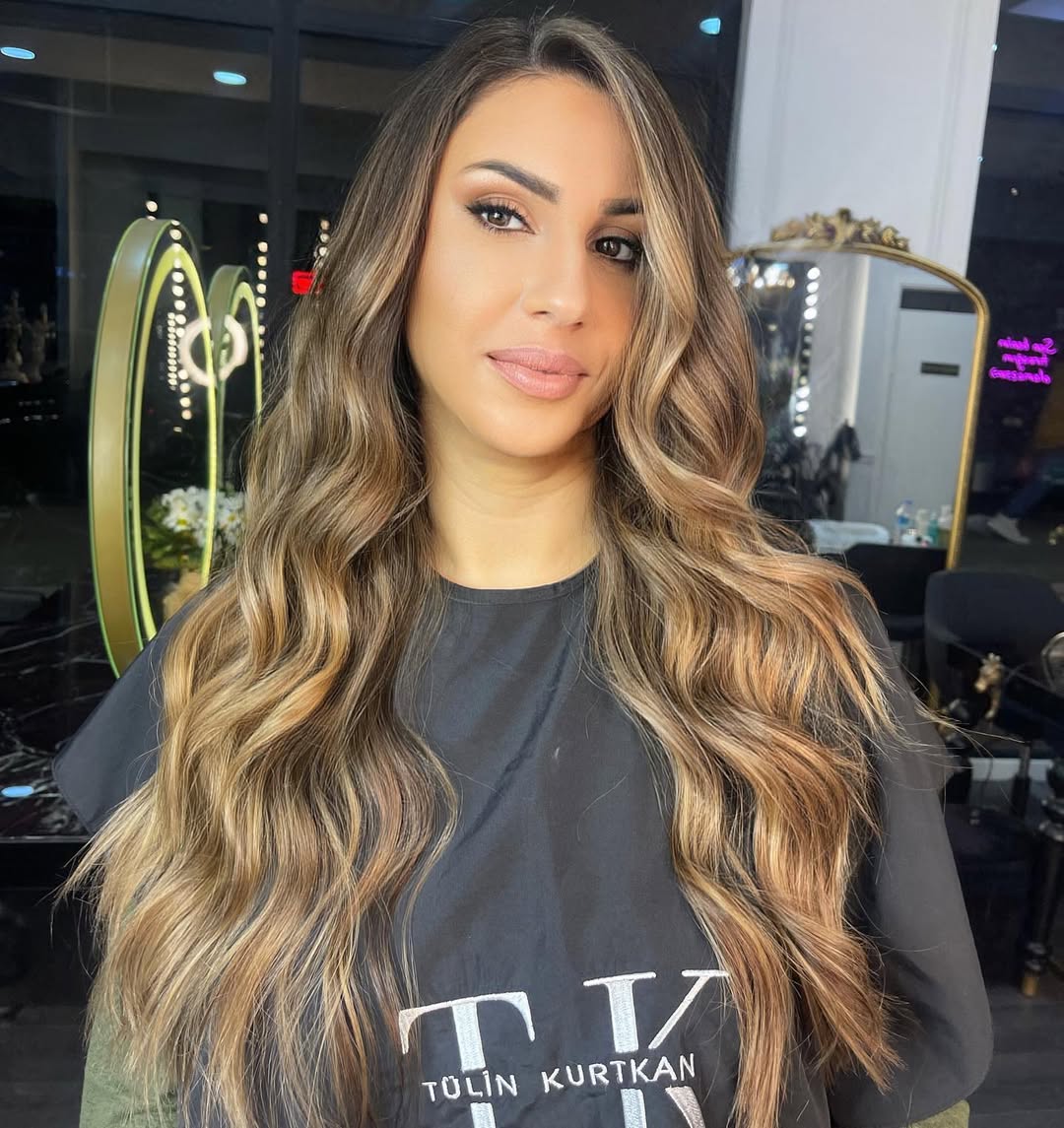 Woman with sun-kissed blonde locks styled in a soft, wavy texture, showcasing a beautiful summer soft hair color 2026. Perfect for a casual daytime look.