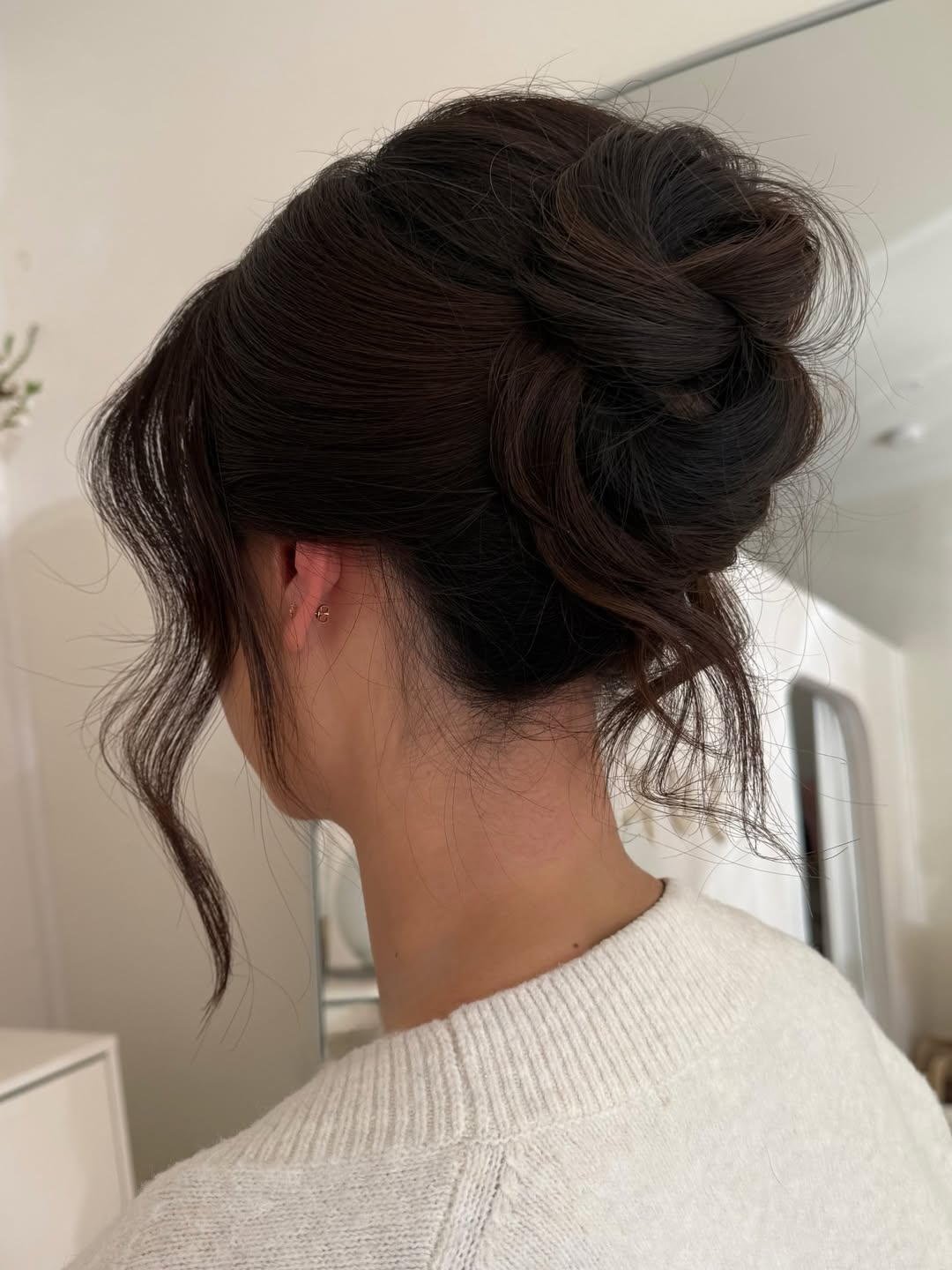 Elegant brunette woman with a chic low braided bun hairstyle, perfect for a summer wedding guest look. Her hair is neatly styled with delicate floral hairpins, ideal for a garden or outdoor ceremony.