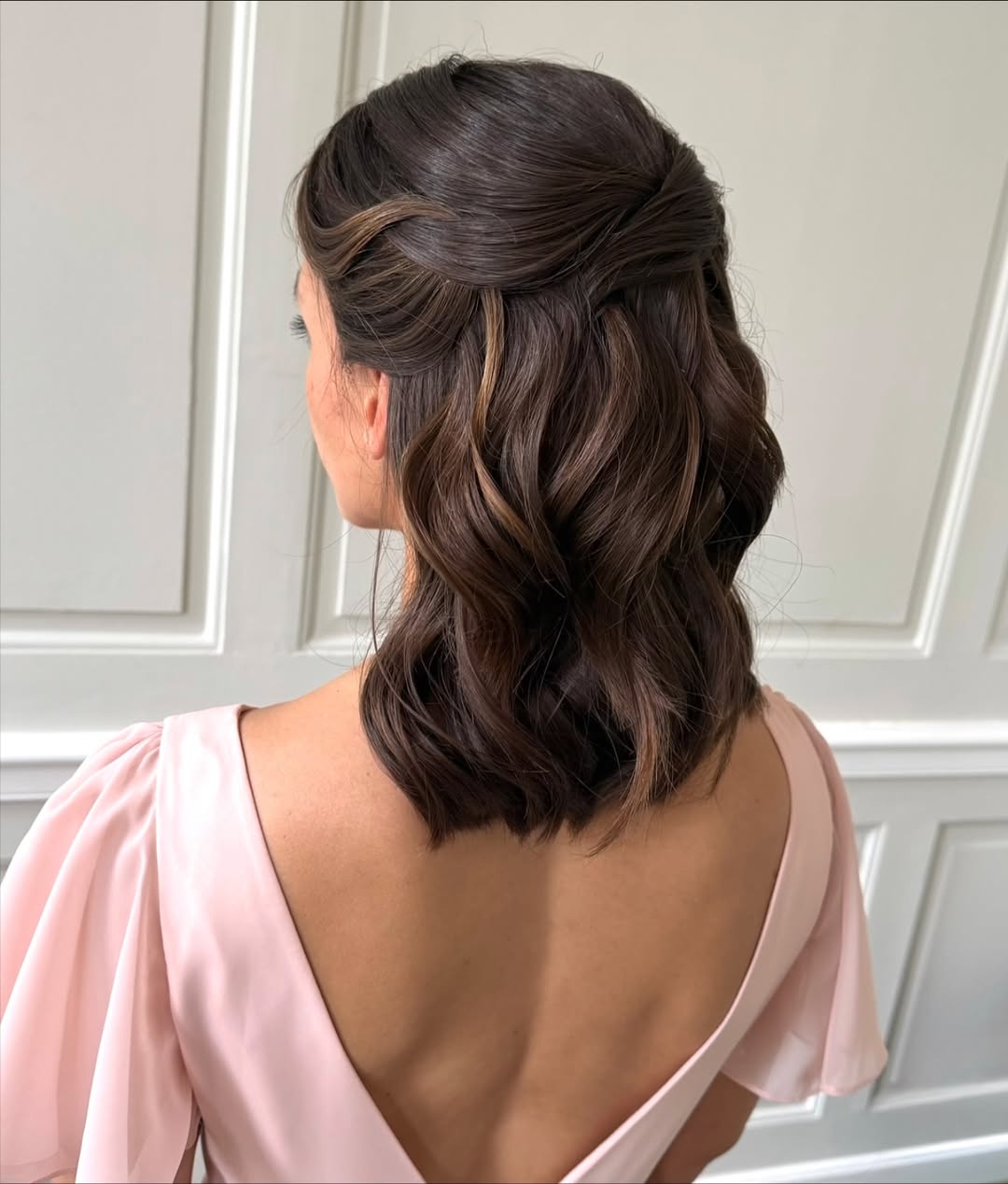 Elegant woman with a half-up braided hairstyle, perfect for a summer wedding guest look. Her dark hair is styled with soft waves, secured with a delicate pearl clip, exuding sophistication for a formal event.