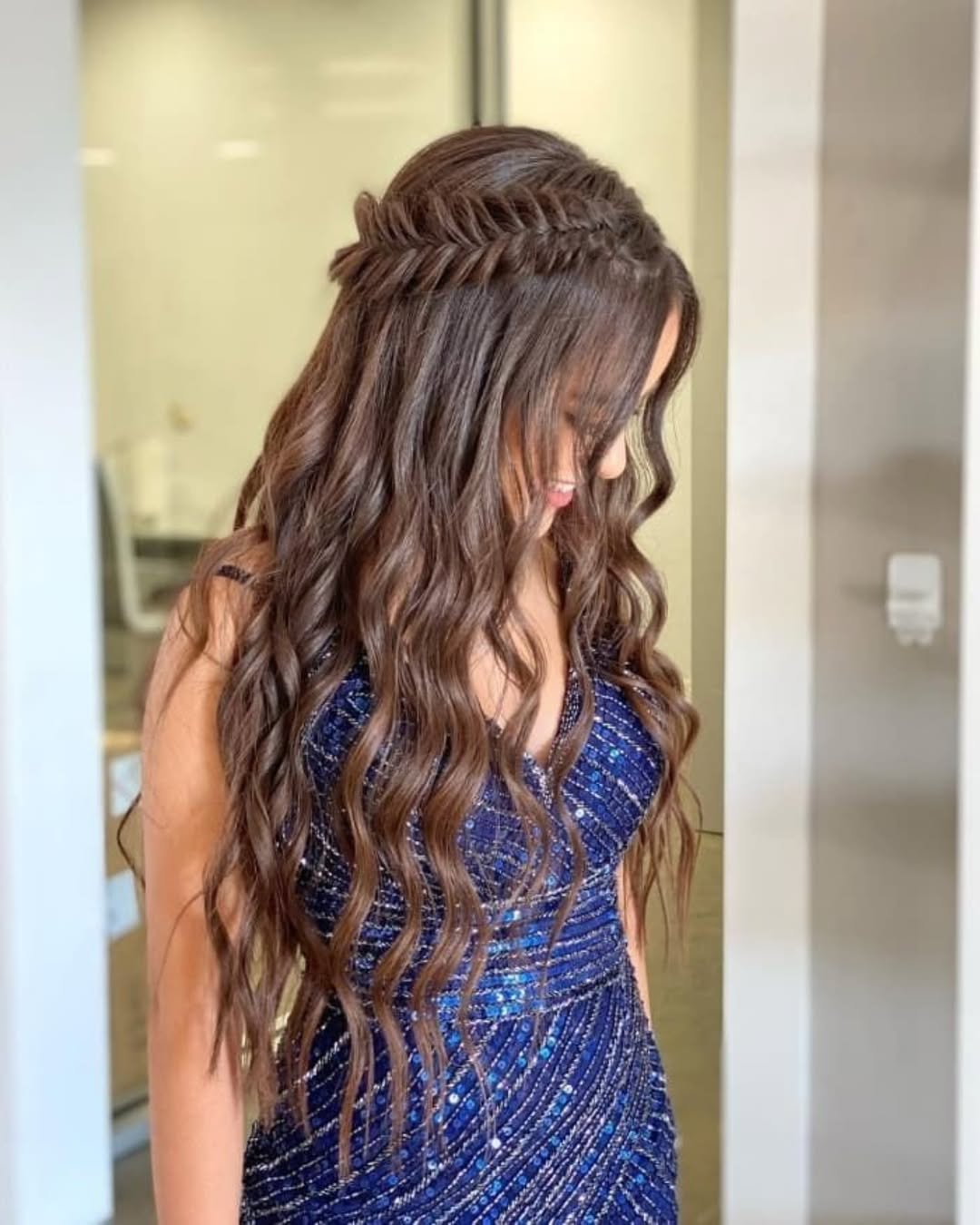 Elegant, curly updo for a summer wedding guest. Dark-haired woman with soft makeup, perfect for a chic and timeless summer wedding guest hairstyle 2026.