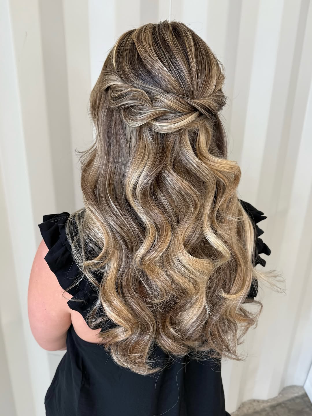 Elegant brunette woman with a sophisticated low chignon, perfect as a summer wedding guest hairstyle. This updo is sleek and polished, ideal for a formal outdoor ceremony or reception. Accessorized with delicate earrings, this look suits various necklines.