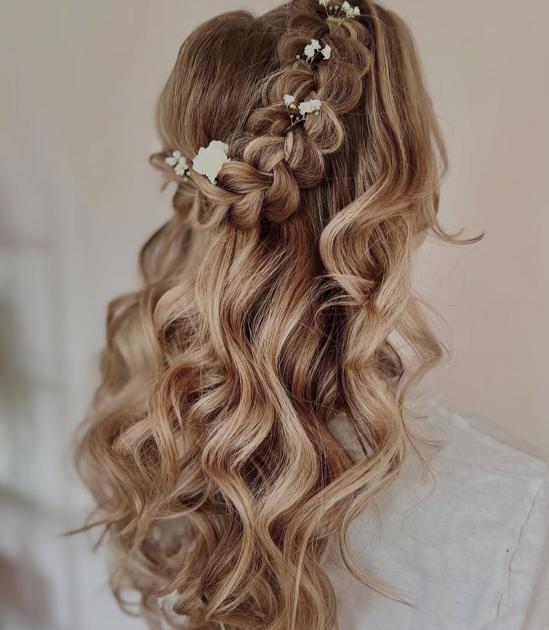 Elegant brunette bride showcasing a half-up braided hairstyle adorned with tiny white flowers, perfect for summer wedding hairstyle ideas 2026.