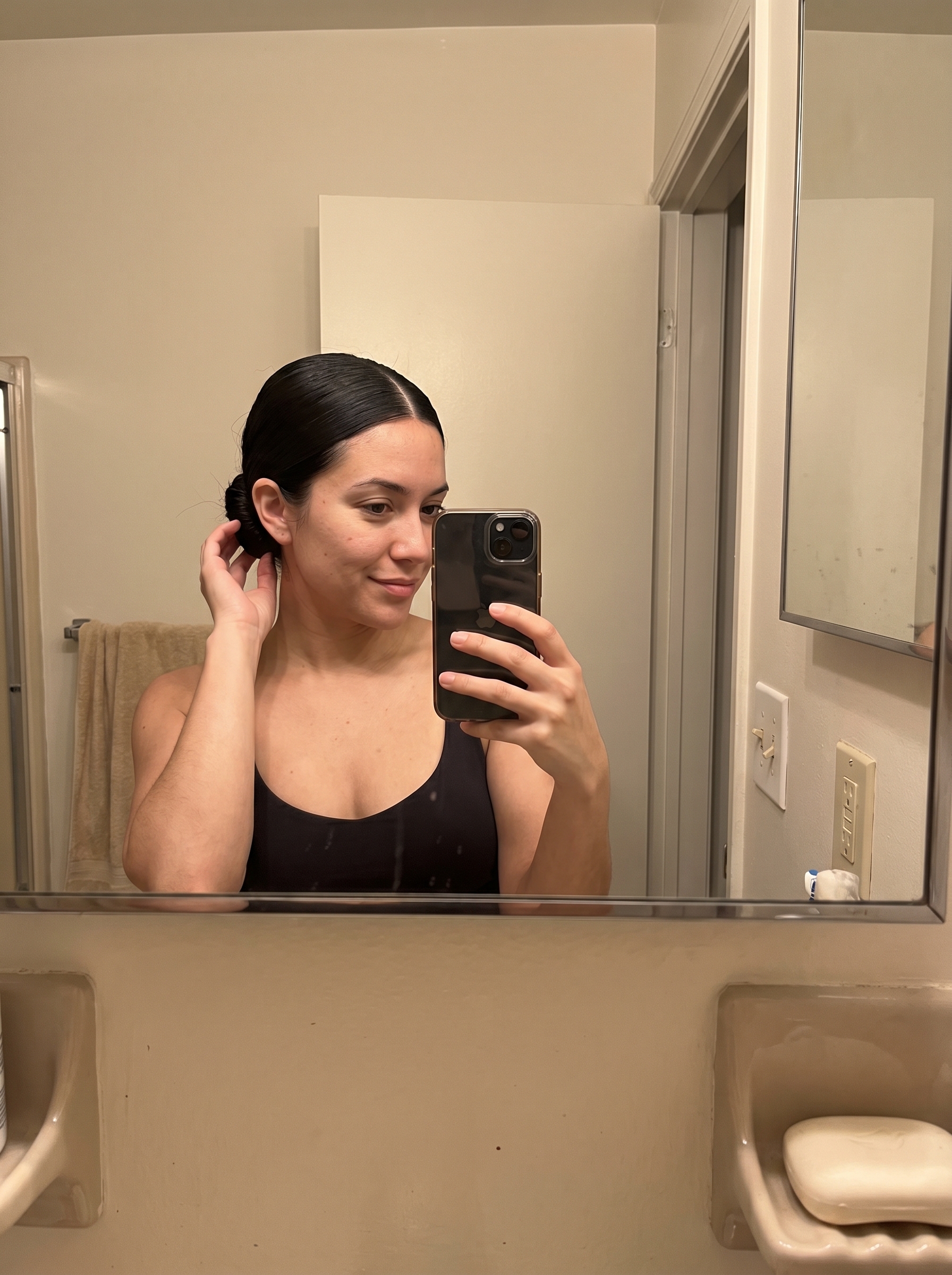 A sleek, minimalist 90s low bun in 'Expensive Espresso' hair, achieved with high-shine pomade and a fine-tooth comb. A chic choice for summer wedding hairstyle ideas 2026.