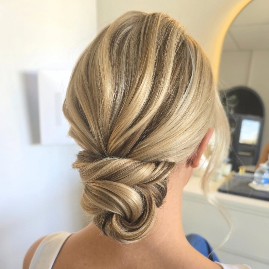 Elegant brunette bride with a soft wavy updo, adorned with delicate white flowers, perfect for summer wedding hairstyle ideas 2026.