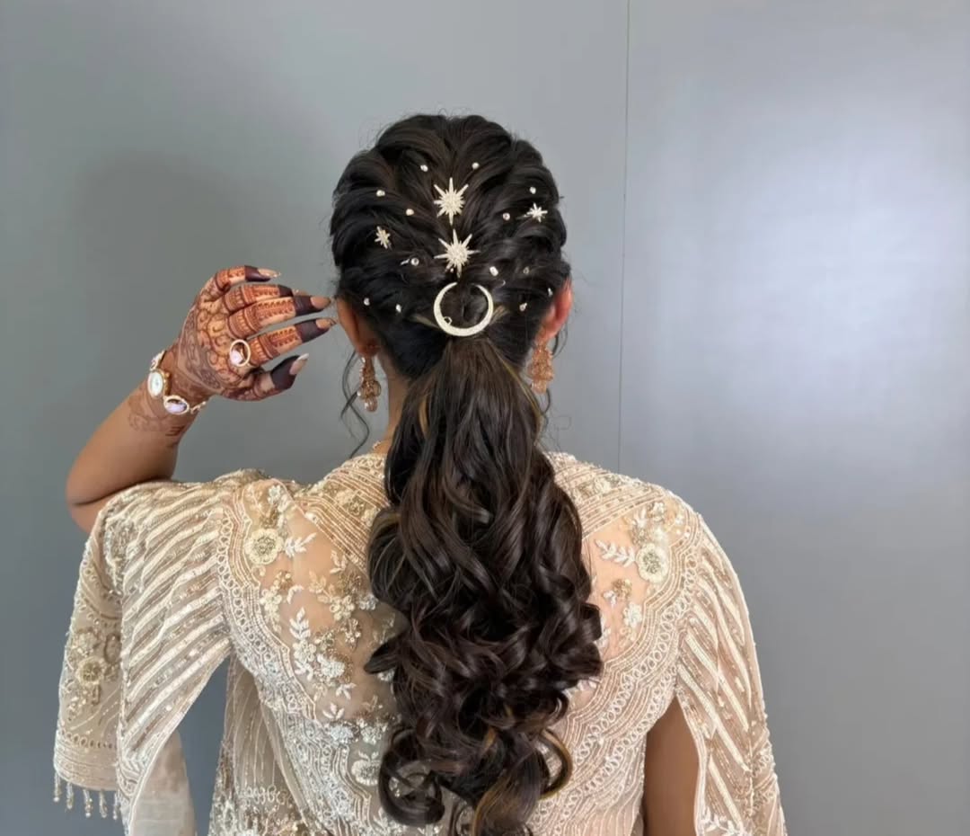 Elegant brunette bride with a soft half-updo featuring delicate braids and small white floral accents, perfect for summer wedding hairstyle ideas. The romantic style complements her off-the-shoulder gown.