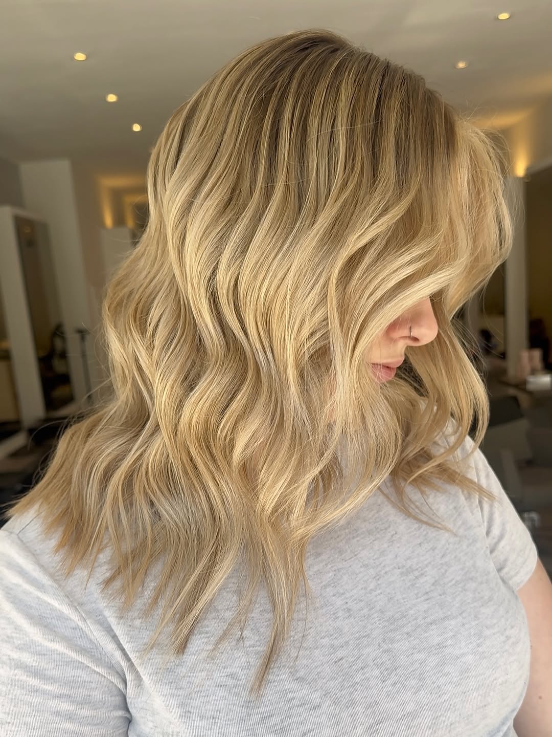 Stunning Beach Waves Hair for Summer 2026 Look! Woman with long, beautifully styled beach waves hair for summer 2026, enjoying a sunny day outdoors. Her golden-brown hair cascades naturally, framing her face perfectly.