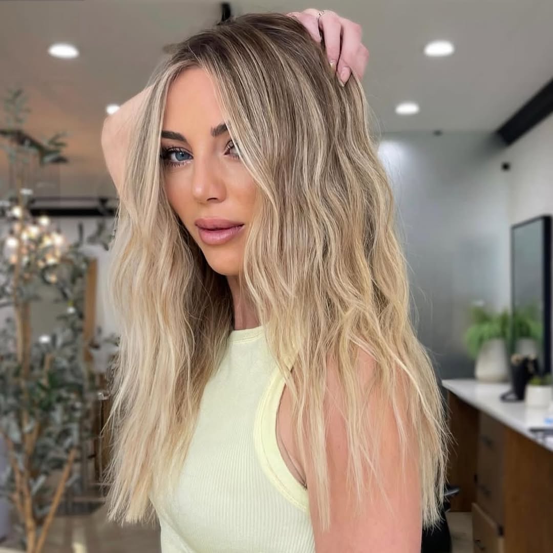 Close-up of a woman with natural, sun-kissed beach waves hair Summer 2026, styled with a layered, casual look perfect for a resort vacation.
