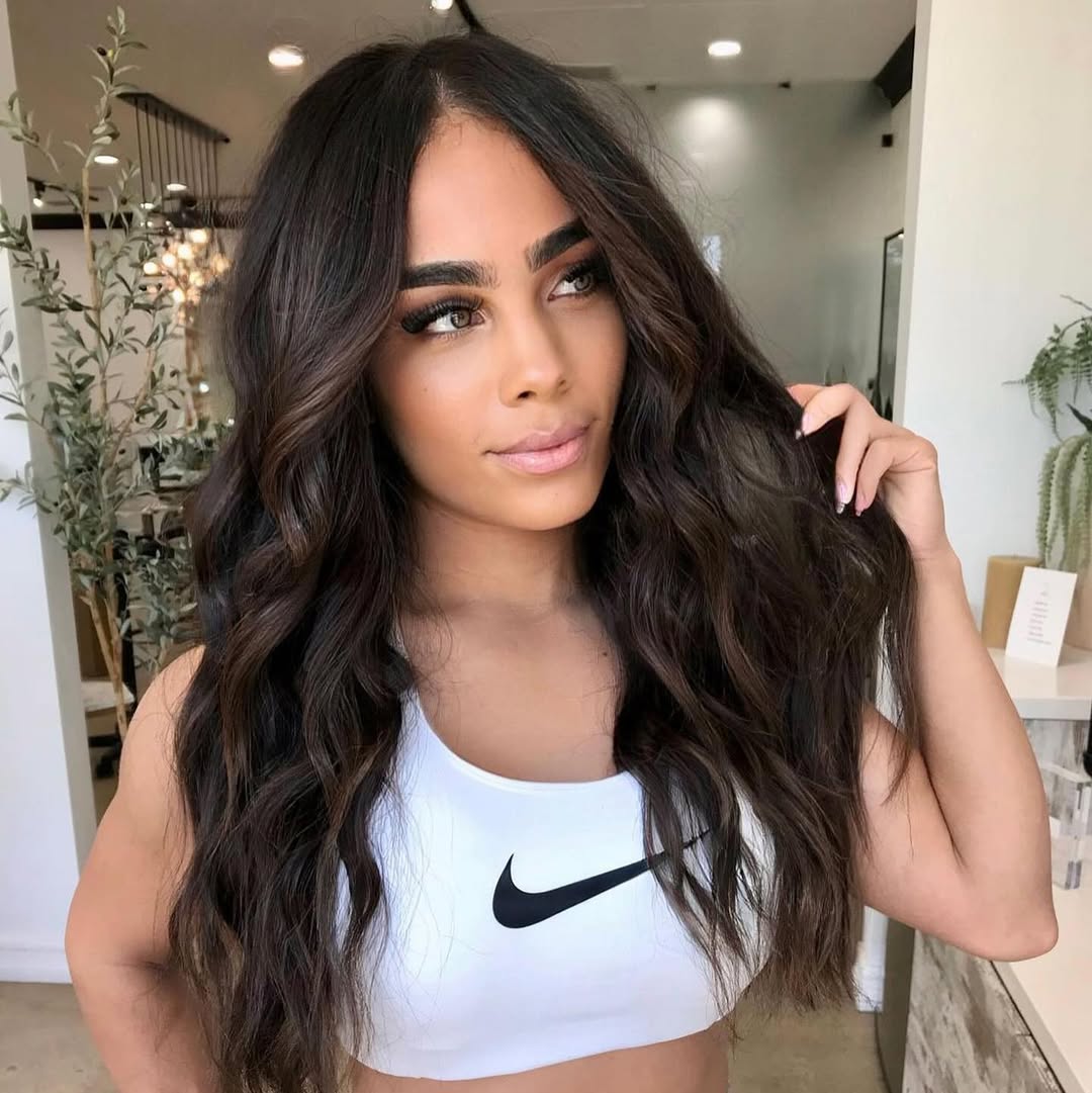 Effortless Beach Waves Hair for Summer 2026 Woman with perfect beach waves hair for summer 2026, wearing a breezy white linen dress and holding a straw bag, enjoying a sunny day by the ocean.