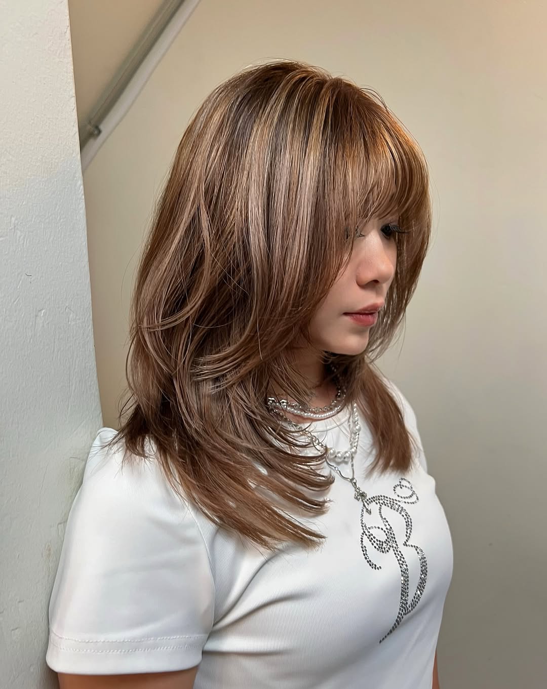 Effortless Wavy Lob: Hairstyles Summer Medium Hair 2026 A woman with a chic, wavy lob haircut featuring subtle blonde highlights, perfect for hairstyles summer medium hair. She wears a flowy white sundress, ideal for a warm, sunny day. Her hair is styled with natural waves, framing her face beautifully.