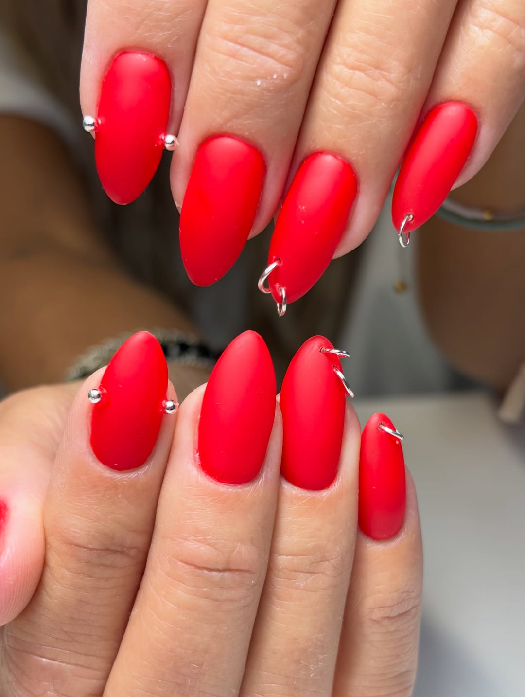 Matte Red Almond Nails With Silver Piercing Details