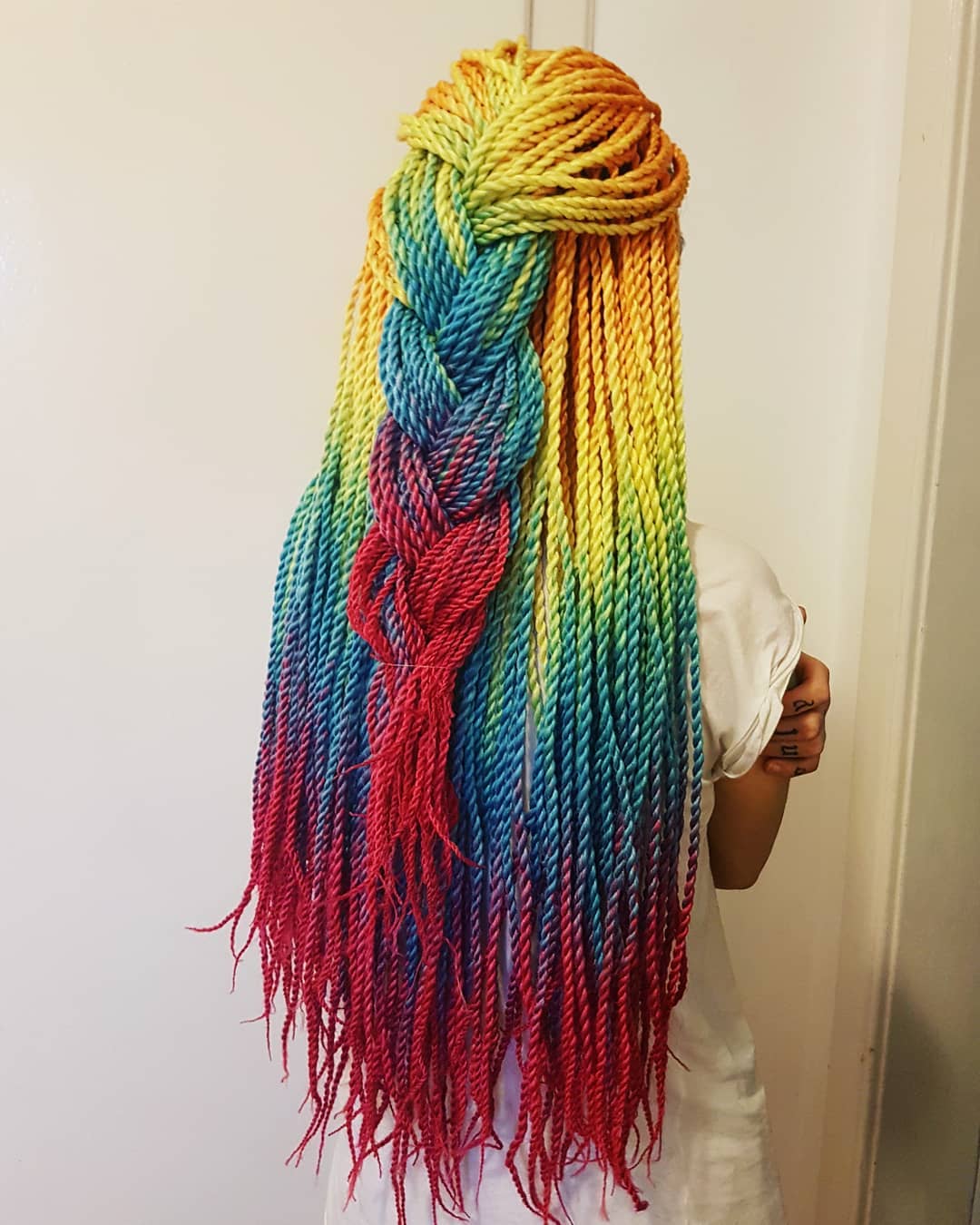 Woman showcasing a chic half-up, half-down twist braid perfect for summer, with sun-kissed highlights, a light blue top, and a confident smile, ideal for casual outings.