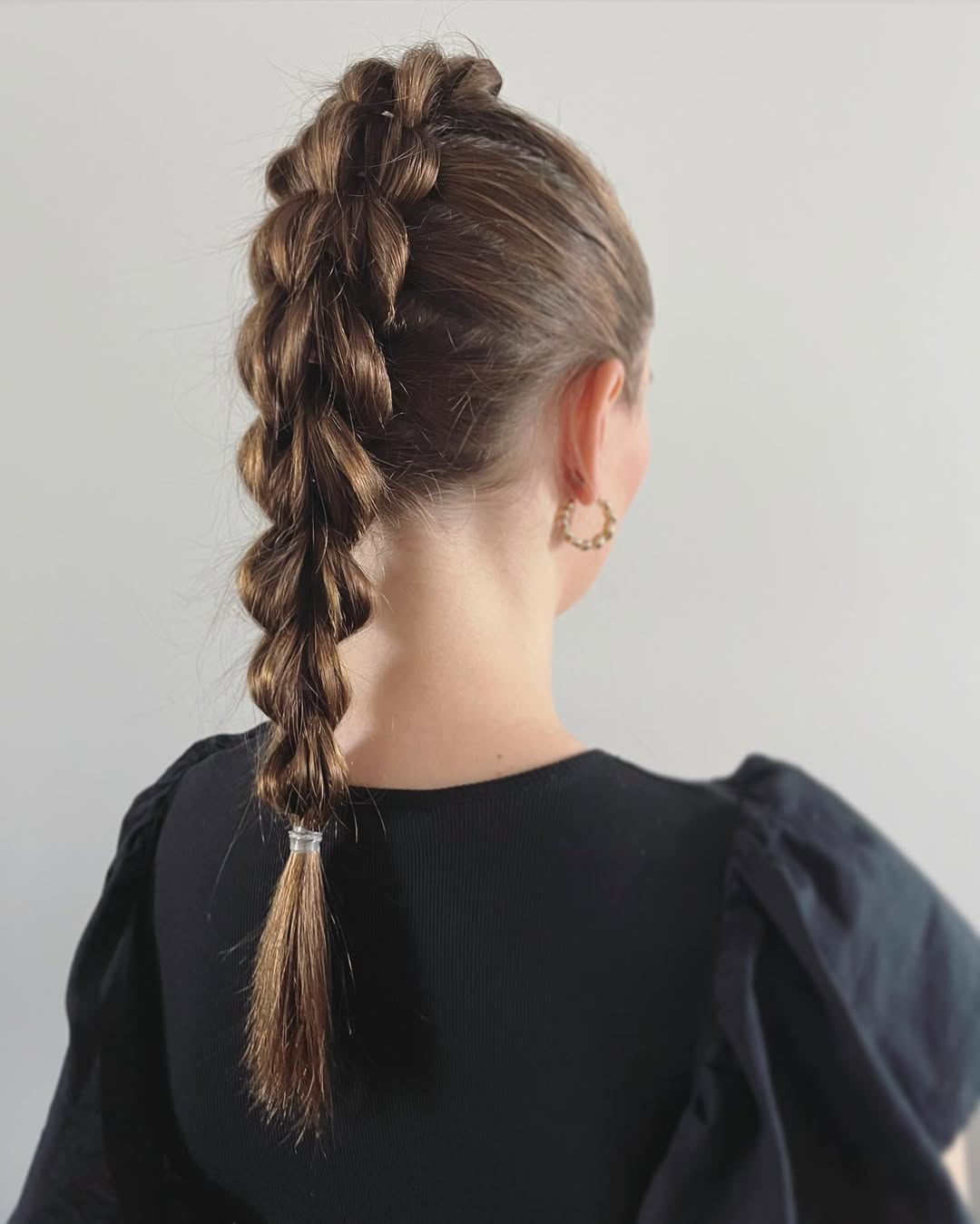 Woman wearing a loose side braid summer hairstyle with face-framing tendrils and a white floral dress, perfect for a casual sunny day. Her hair has blonde highlights.
