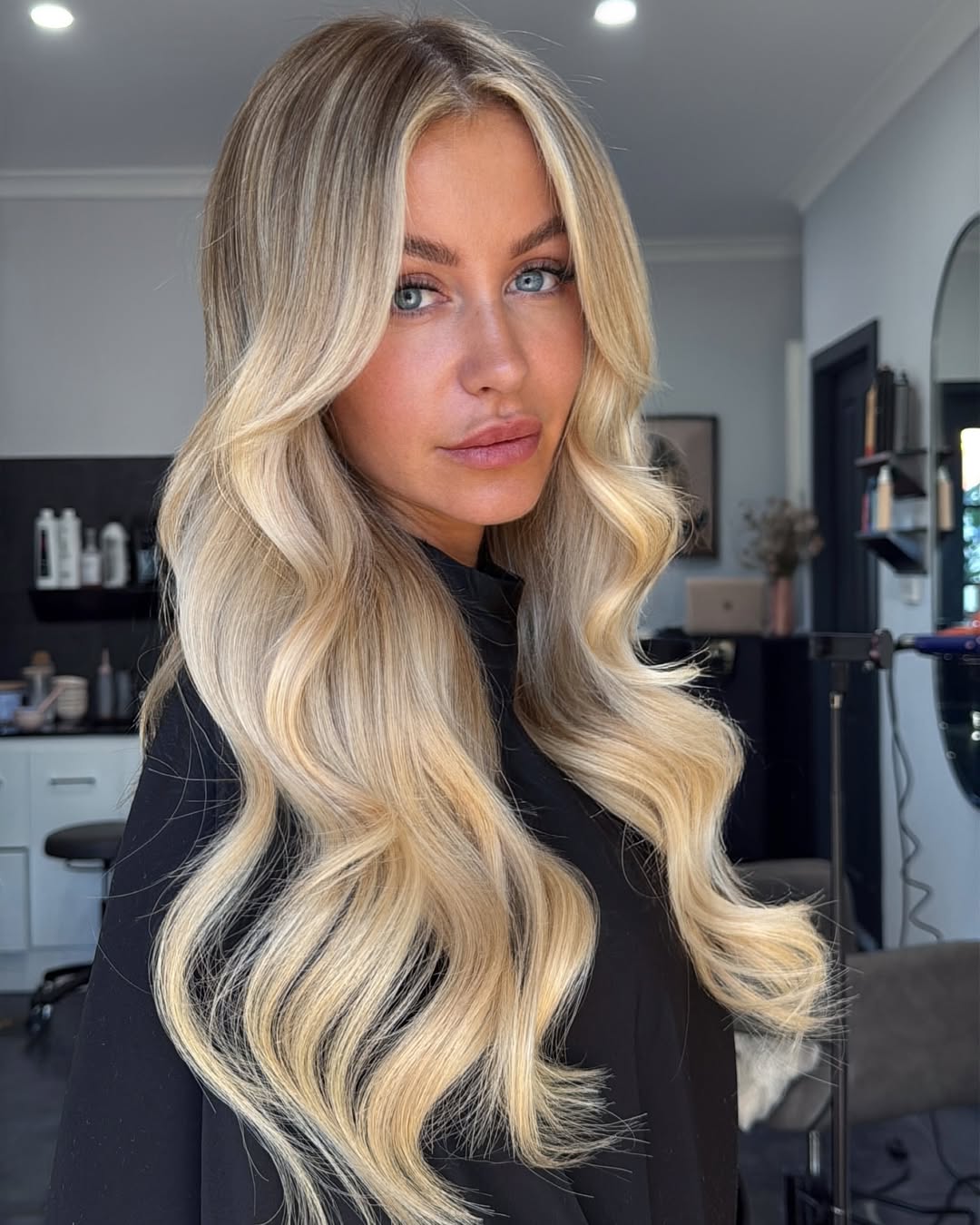 Close-up of a woman with long, sun-kissed blonde hair styled in loose beach waves, perfect for summer cool hair ideas 2026. Her hair is effortlessly flowing, suggesting a relaxed summery vibe.