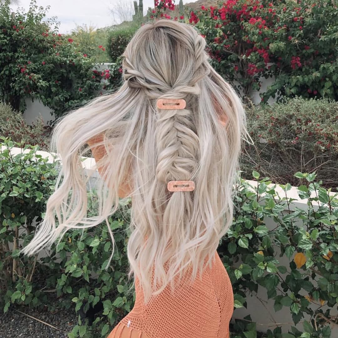 A woman with a cute half-up braided hairstyle, perfect for summer. Her brown hair is intricately woven at the crown with loose waves flowing down, showing off a stylish and breezy look for any casual outing.