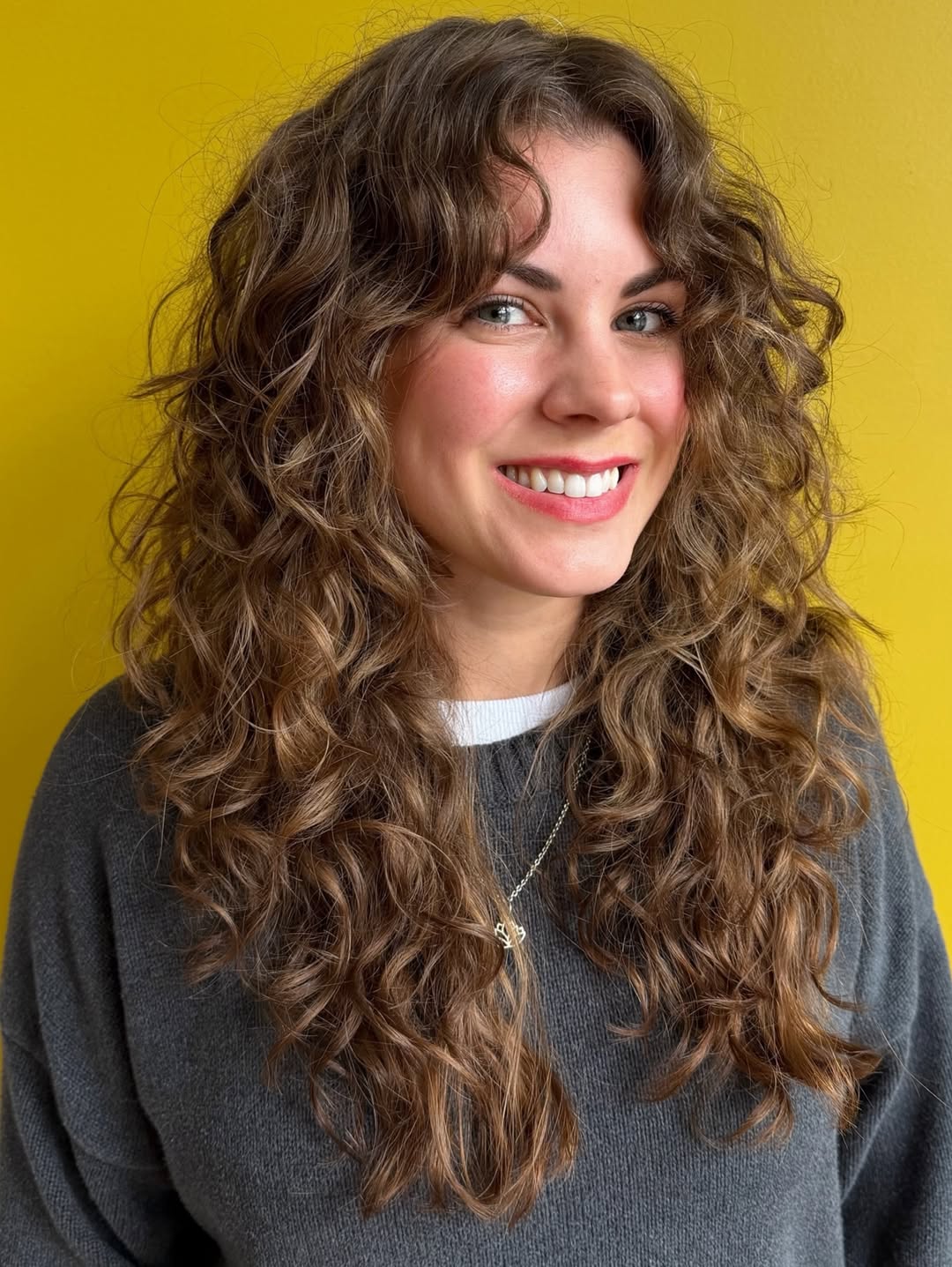 Beautiful woman with voluminous, perfectly defined summer hair curly ideas 2026, showcasing healthy, bouncy curls styled for a sunny day.