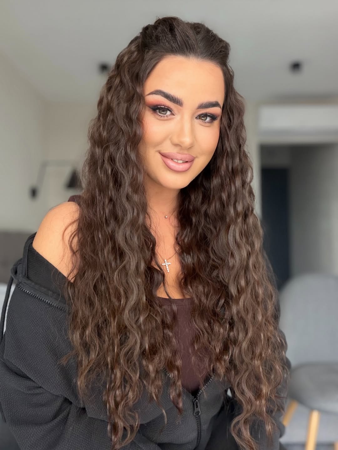 Close-up of a smiling woman with voluminous, natural summer hair curly ideas 2026, styled with a soft side part.