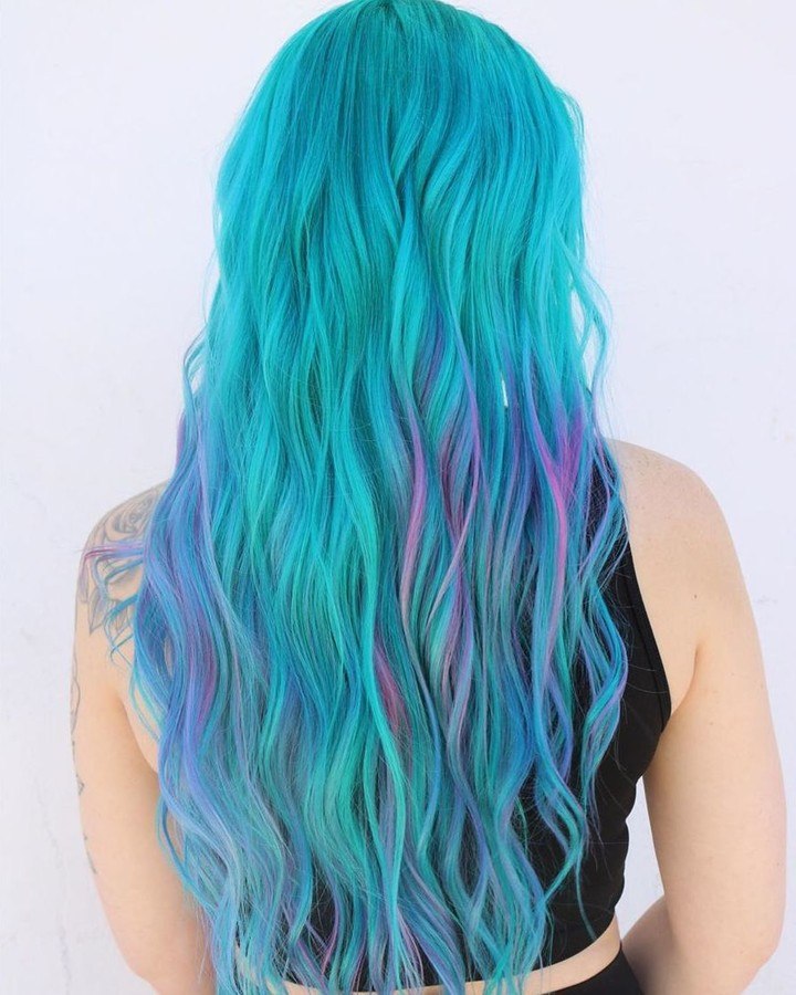 Model with vibrant purple hair in a cute wavy bob, perfect for summer hair cute colors 2026. She wears a casual white top, showcasing a fun and playful style.