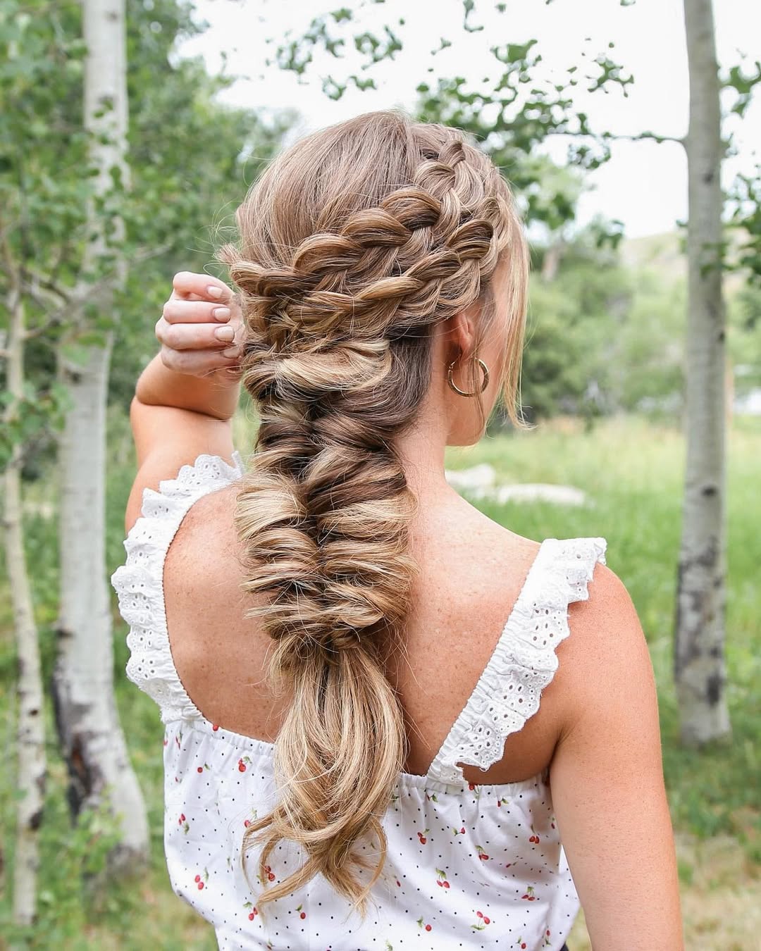 Close-up of a woman with long, sun-kissed blonde hair styled in soft, beachy waves, perfect for summer hair trends 2026. She wears a delicate gold necklace.