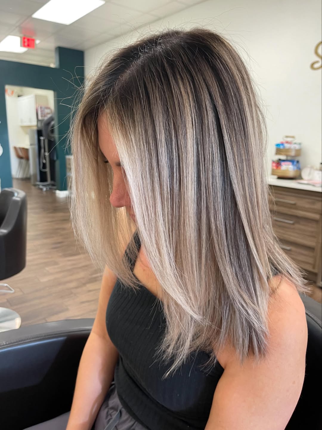 Woman with long, wavy blonde hair styled in loose beach waves, perfect for summer hair trends 2026. She wears a flowy white sundress, suggesting a casual daytime or vacation look.