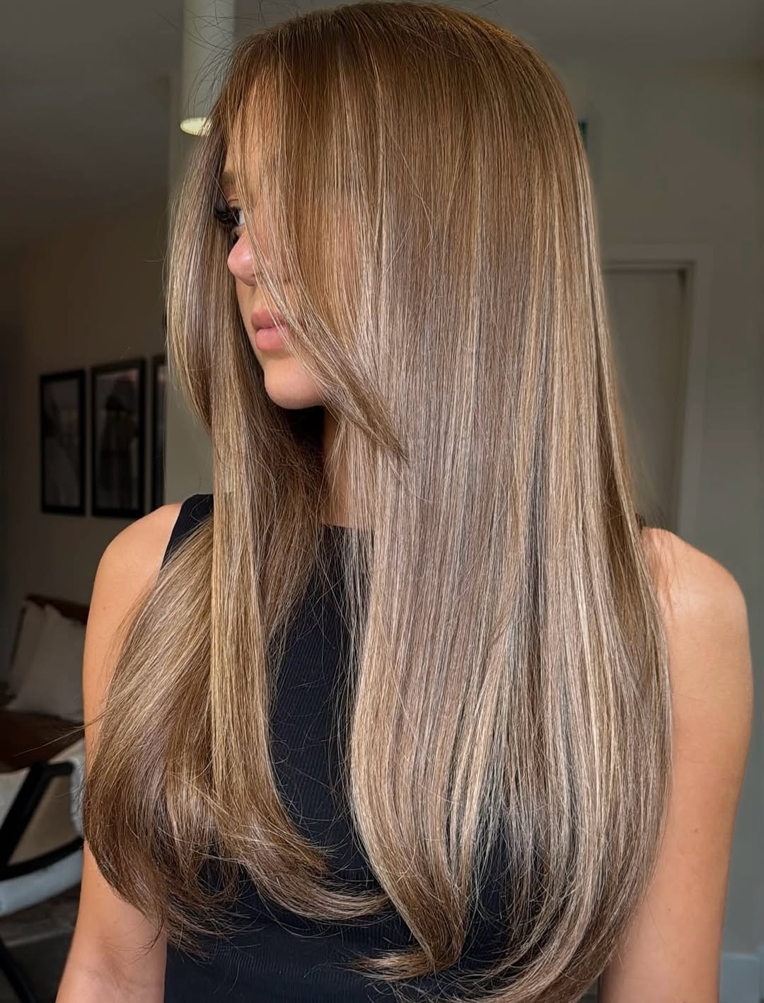 Close-up of a woman with long, sun-kissed blonde hair styled in loose beach waves, showcasing popular summer hair trends 2026. She wears a white lace top, perfect for a casual day out.