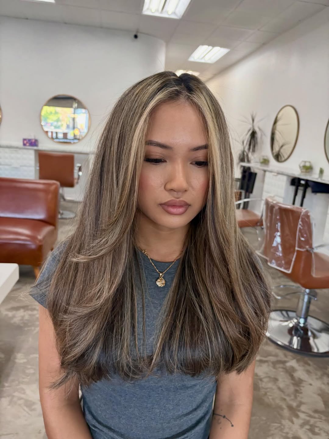 Close-up of a woman with long, sun-kissed blonde hair styled in soft, beachy waves, showcasing summer hair trends 2026. Her hair is parted down the middle, framing her face perfectly.