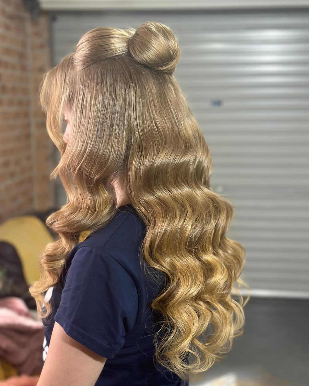 Beautiful blonde woman laughing, showcasing a chic high braided bun perfect for summer hair updos, styled with loose face-framing tendrils and delicate gold earrings for a romantic vibe.