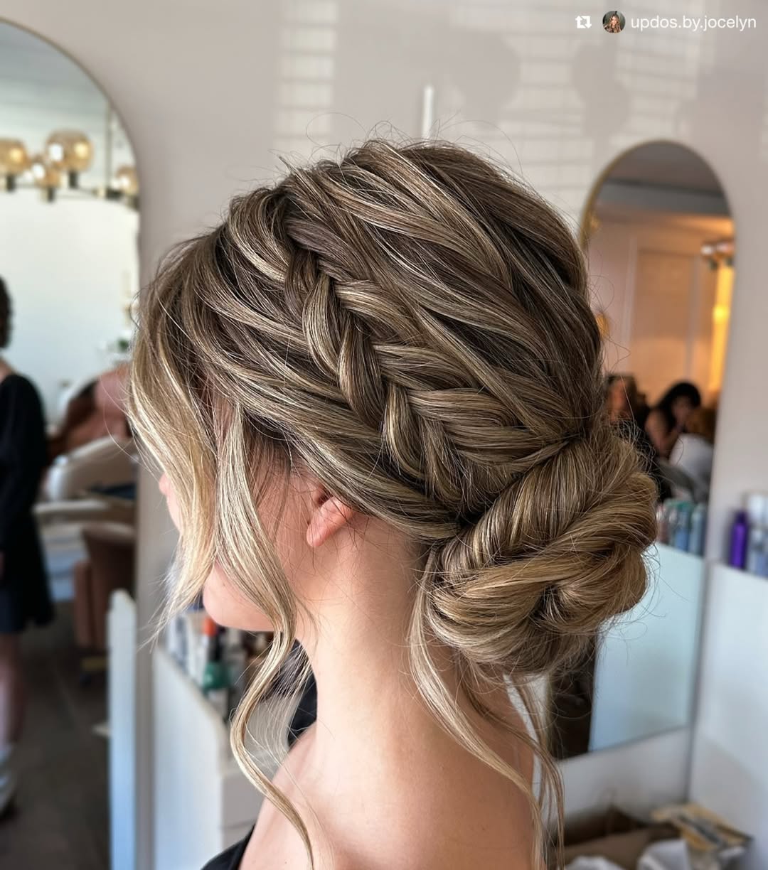 Blonde woman with a chic high bun, perfect for summer hair updos, wearing a casual white off-shoulder top for a relaxed outdoor look.