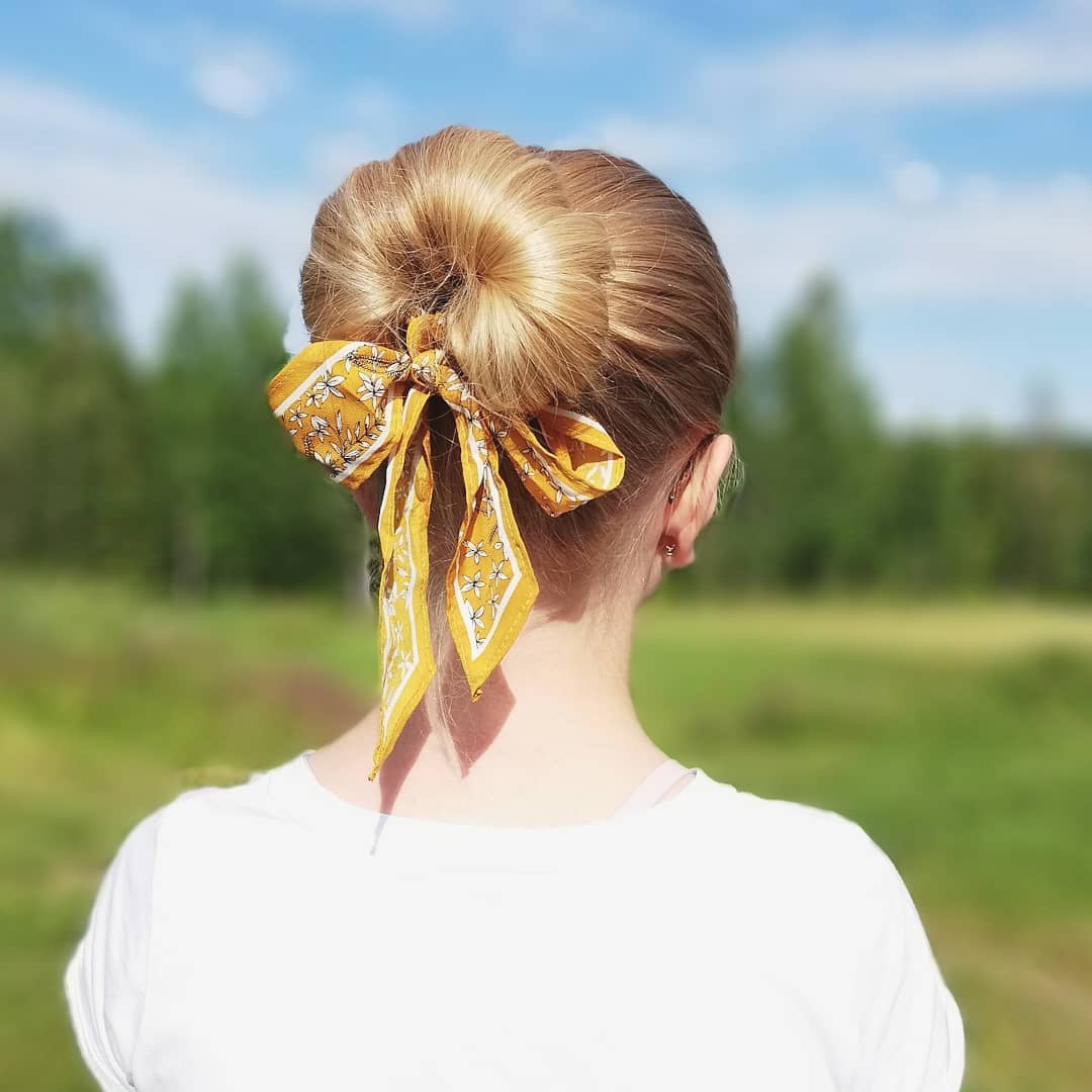 Elegant woman with a chic low bun showcasing a perfect summer hair updo. Her blonde hair is neatly styled, ideal for a sophisticated evening event or a casual brunch. This classic updo keeps hair off the neck, offering comfort and style.