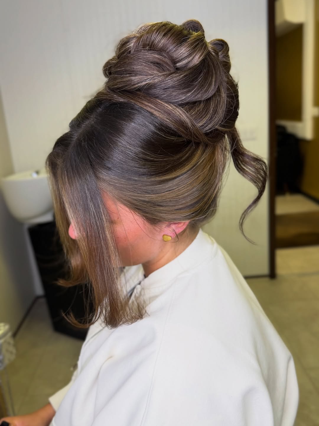 Elegant brunette woman with a high, messy bun showcasing a chic summer hair updos 2026 style for a casual day.