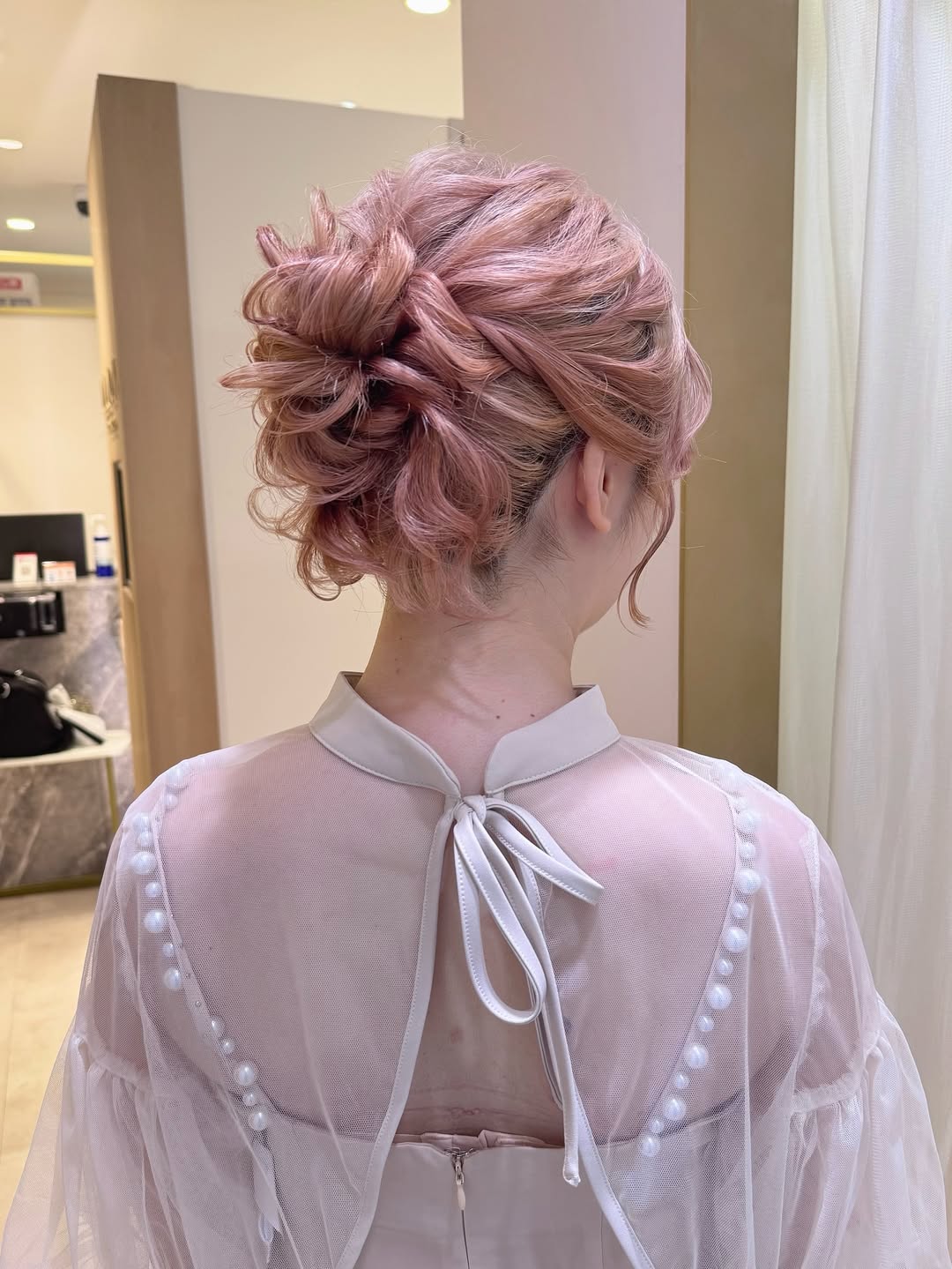 Beautiful blonde woman sporting a chic messy bun summer hair updo, perfect for a casual sunny day. Her hair is loosely tied with delicate strands framing her face, ideal for summer.