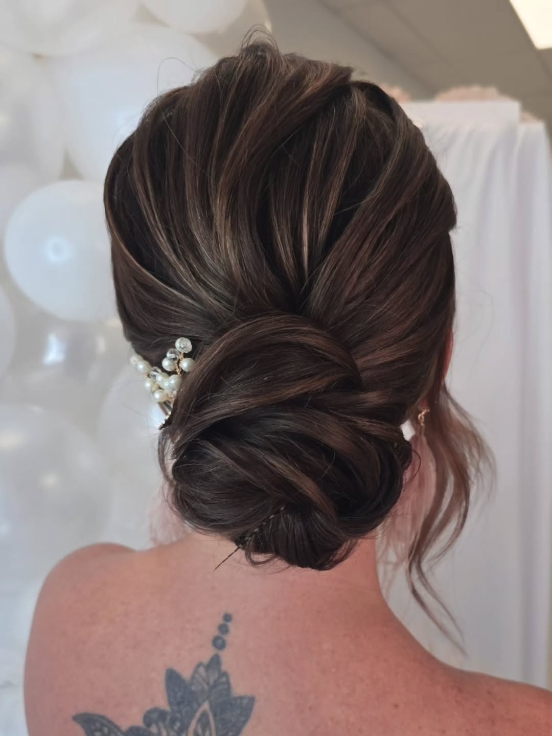 Blonde woman with a chic, messy high bun offering a perfect summer hair updo. Sun-kissed hair styling for casual outings.