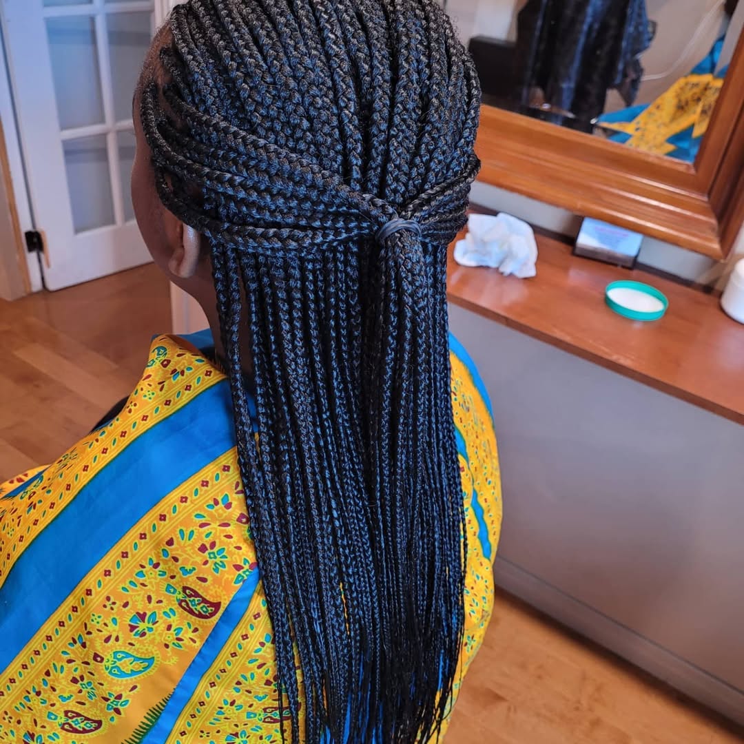 Beautiful Black woman with an elegant, pulled-back braided bun hairstyle, perfect for formal summer events. This stylish look showcases one of the best summer hairstyles black women 2026 options.