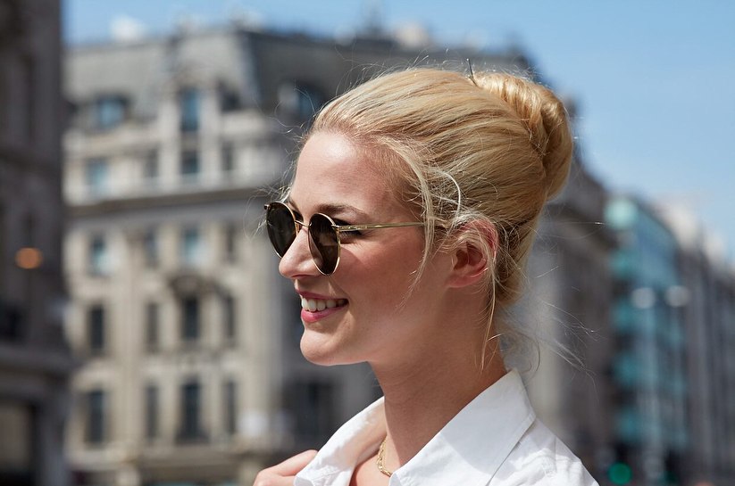 A woman confidently stands, showcasing beautiful and practical summer hairstyles hot weather. Her hair is styled in a loose, voluminous high ponytail with soft waves, perfect for keeping cool and chic during warm days. The look is effortless and elegant for a daytime outing or a casual evening event.