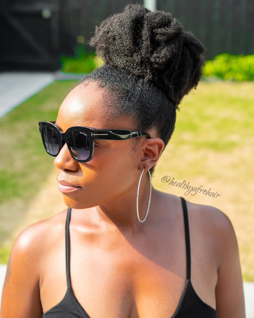Woman with a stylish high ponytail, a perfect summer hairstyle for hot weather, wearing a white button-down and denim shorts.