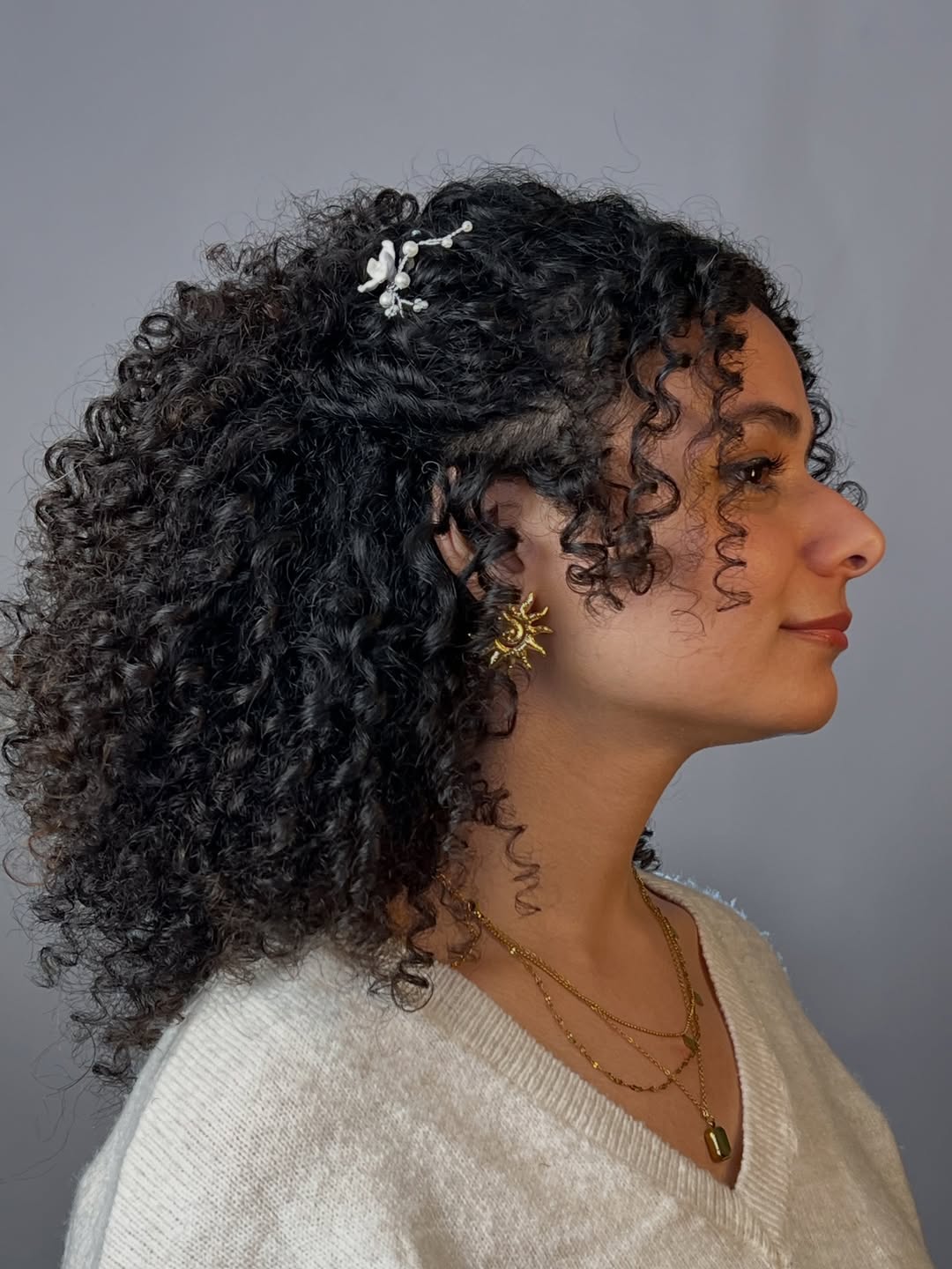 Defined Medium Curly Hairstyle With White Hair Pin