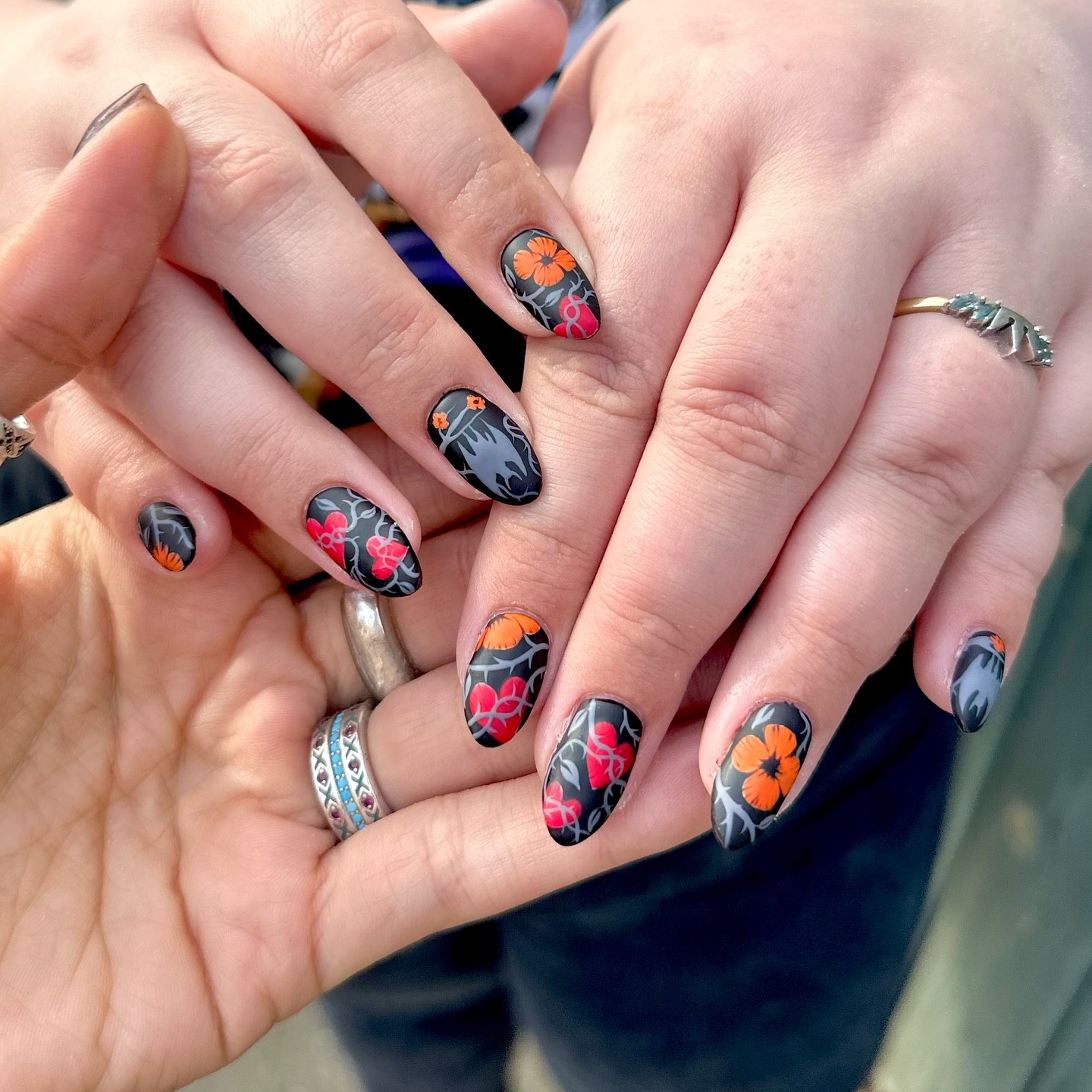 Matte Black Floral Almond Nails with Orange Accents