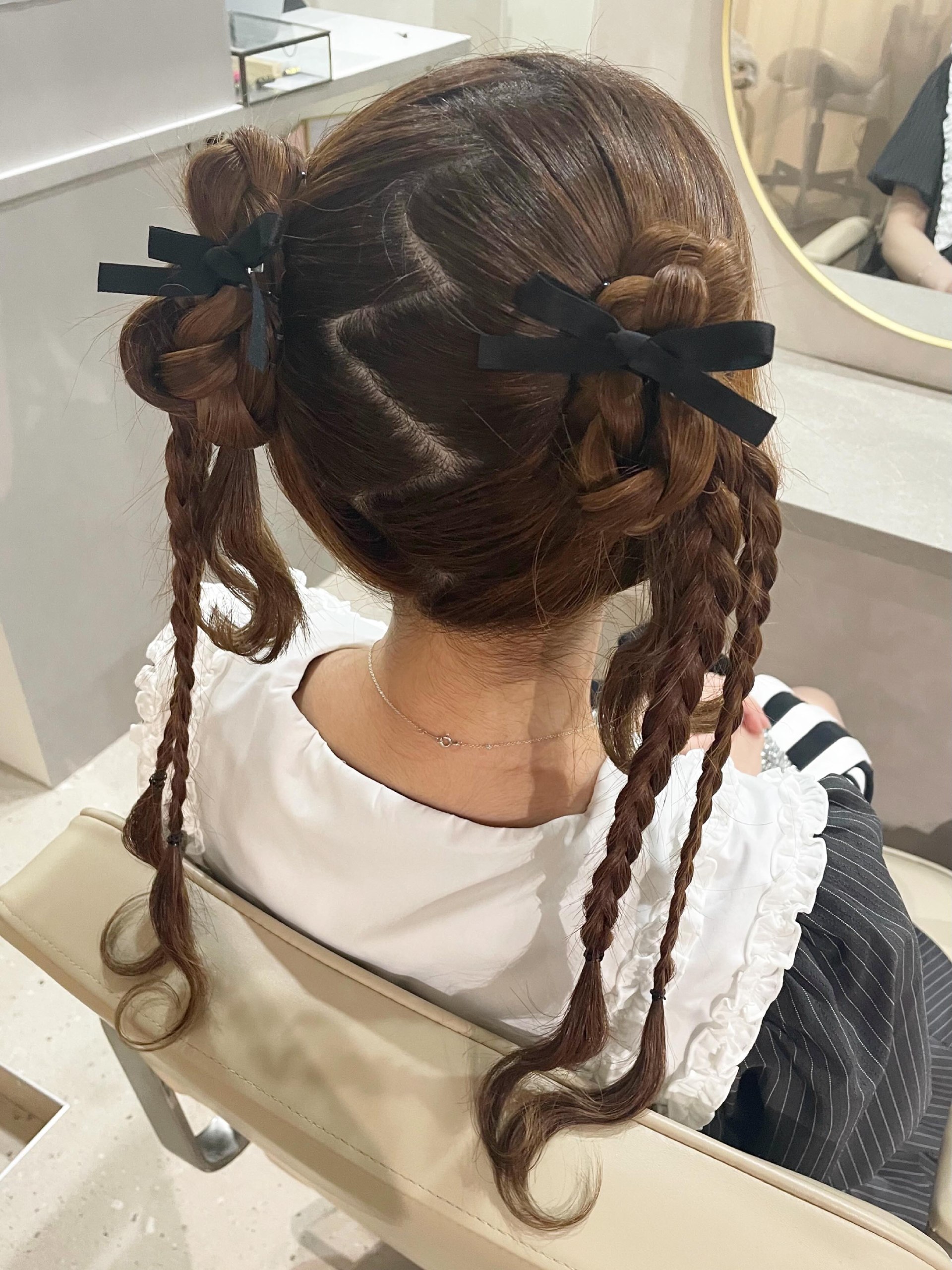 Braided Space Buns With Loose Curls And Black Bows