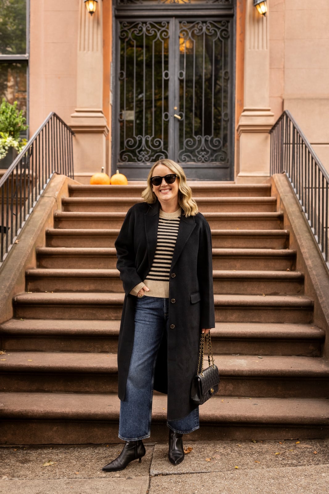 Long black coat over striped sweater and wide-leg jeans — Cold Weather Outfits